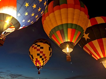 Several hot air balloons glowing at dawn hovering in the sky